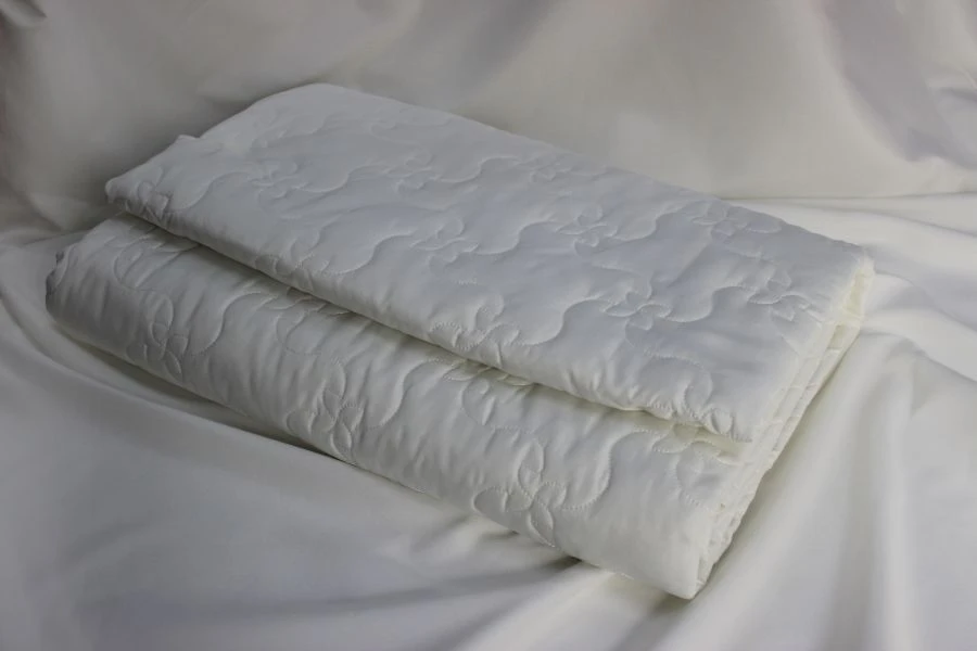 Quilted coverlets of cotton and synthetic fabrics, filled with cotton and synthetic fibres.